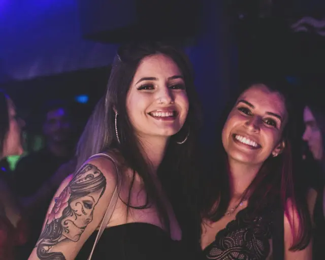 Zwei Frauen feiern lachend auf einer Latin-Party